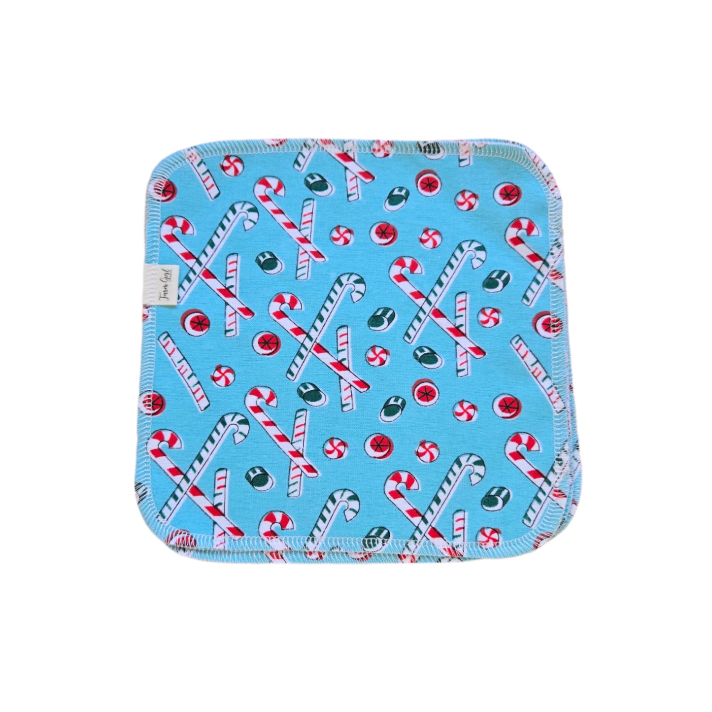 A blue cloth napkin with a Christmas-themed pattern, featuring candy cane and peppermint designs.