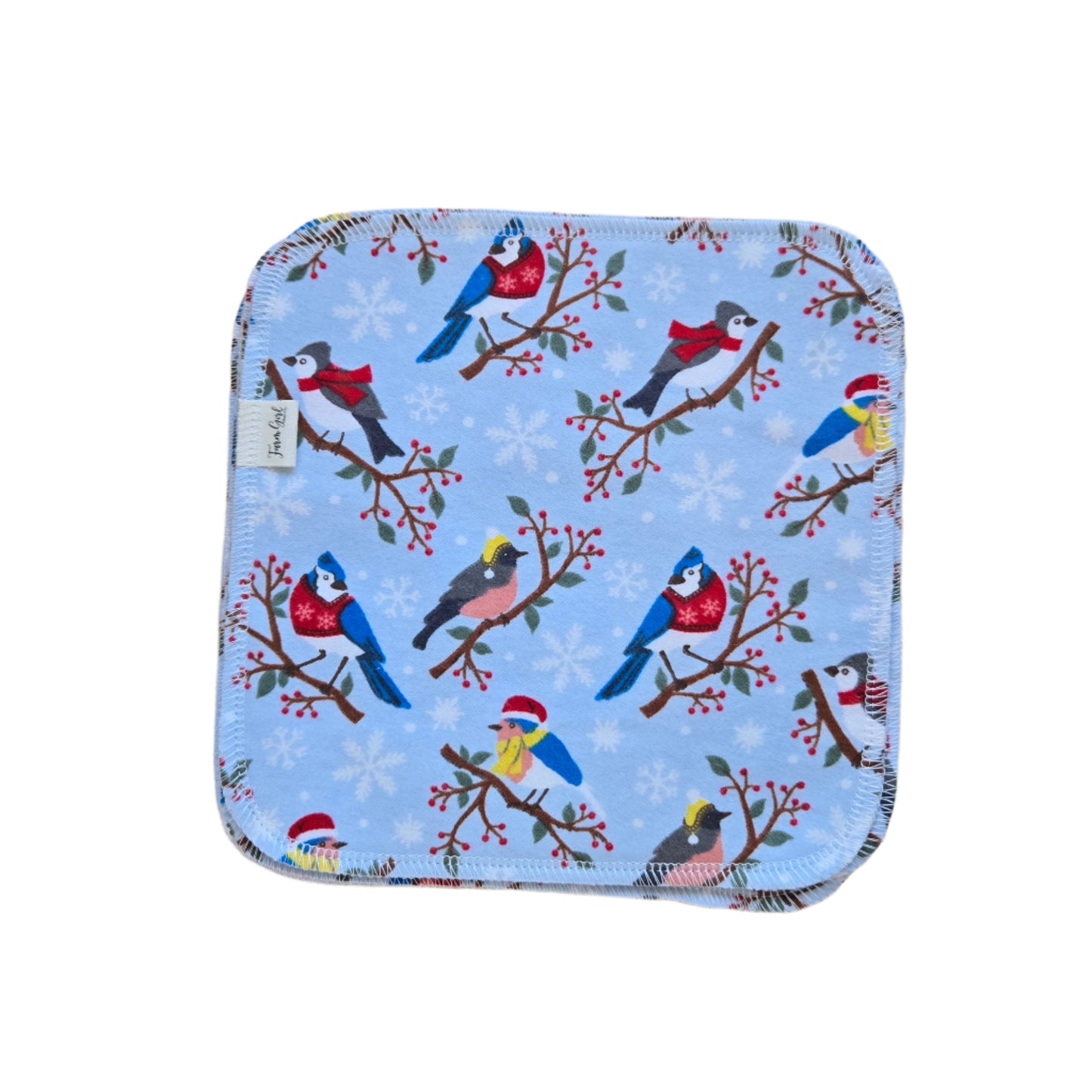 A cloth napkin with a winter songbirds pattern, featuring various birds perched on branches against a snowy blue background.