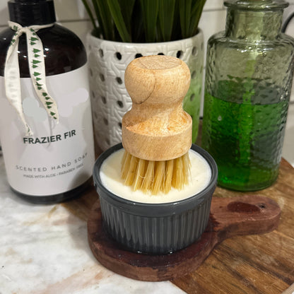 solid dish soap in a ramekin with a wood handle scrub brush.