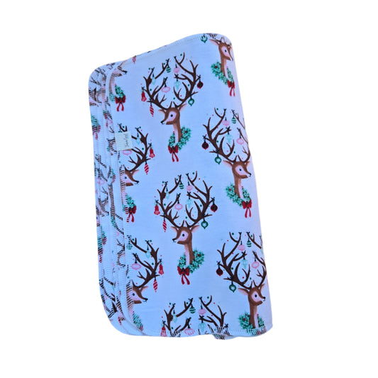 A stack of white paperless towels with a decorated reindeer pattern on a wooden surface.