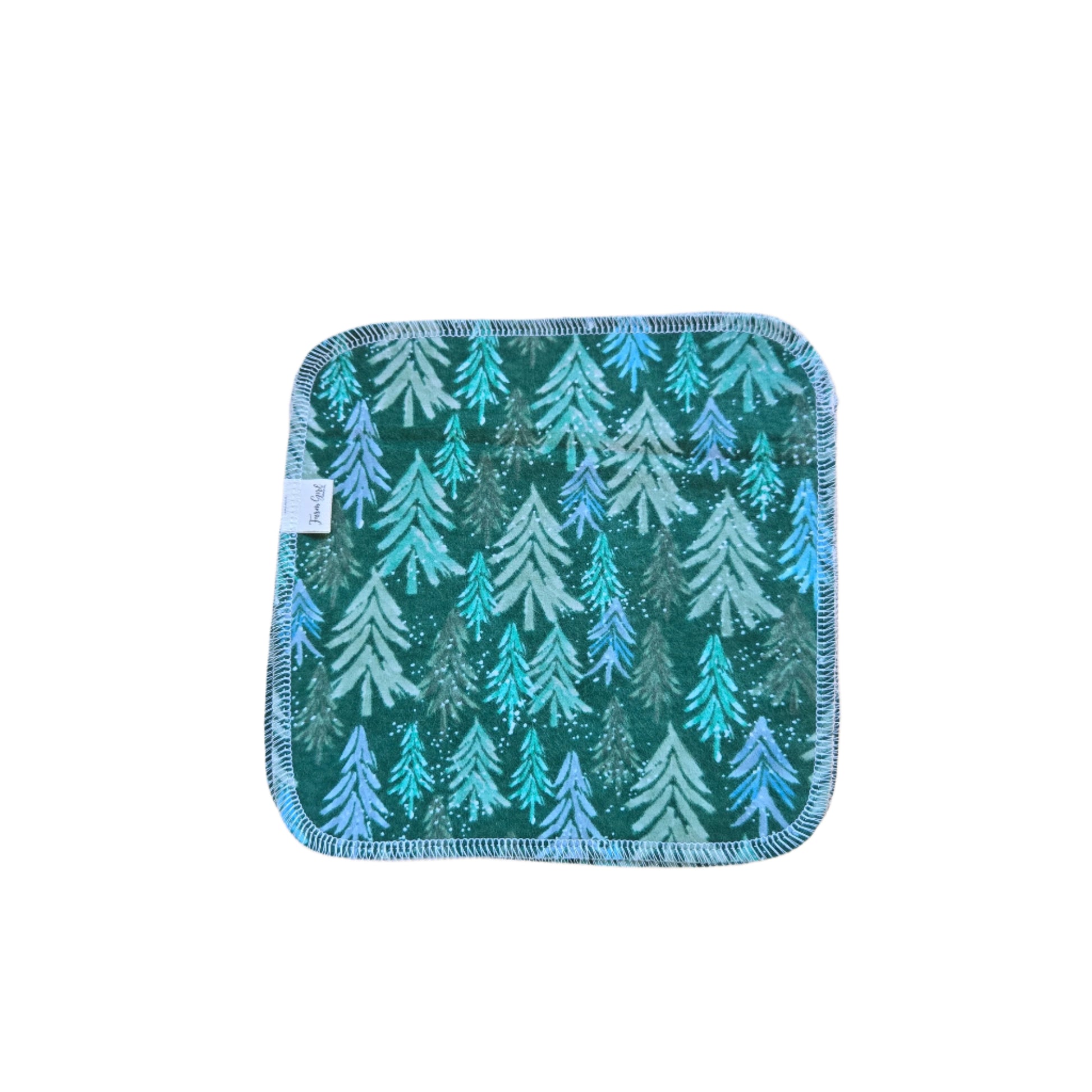 A green cloth napkin with a sparkling forest pattern placed on a wooden surface.
