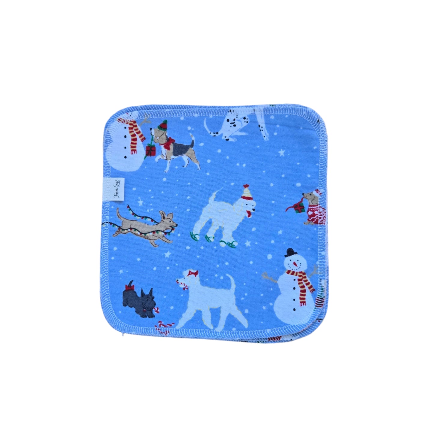 A blue cloth napkin with a winter-themed design featuring cartoon dogs, snowflakes, and a Santa Claus figure.