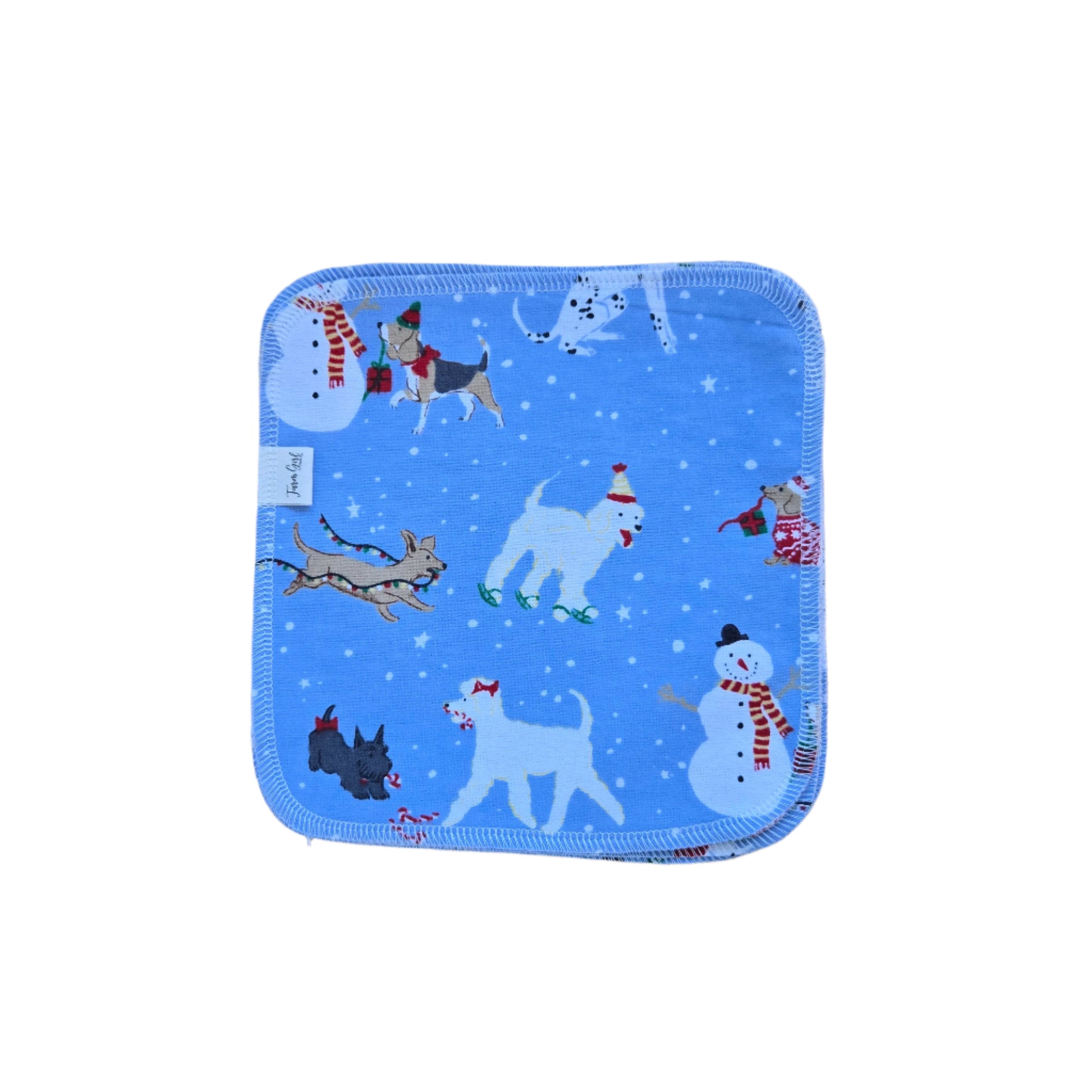 A blue cloth napkin with a winter-themed design featuring cartoon dogs, snowflakes, and a Santa Claus figure.