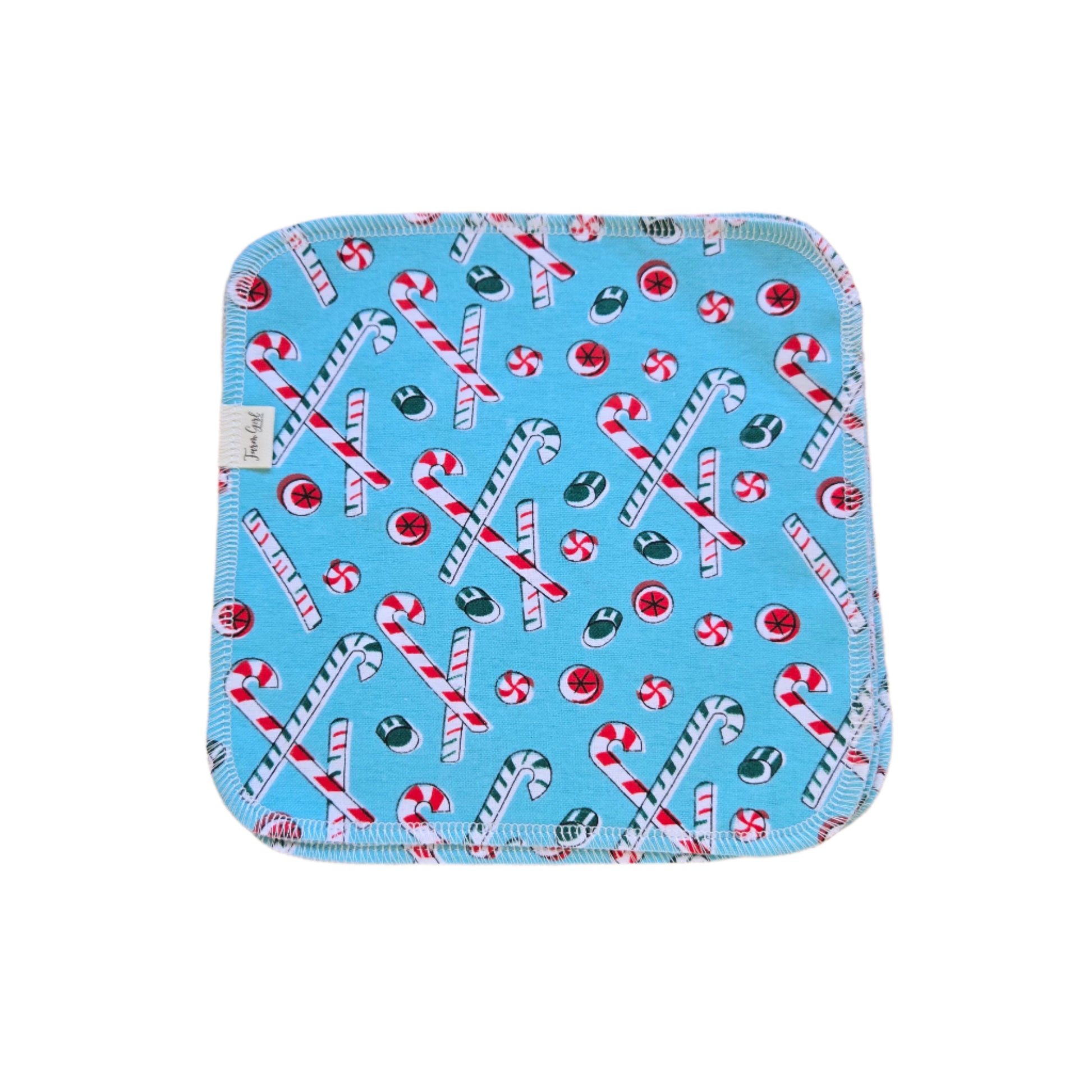 A blue cloth napkin with a Christmas-themed pattern, featuring candy cane and peppermint designs.