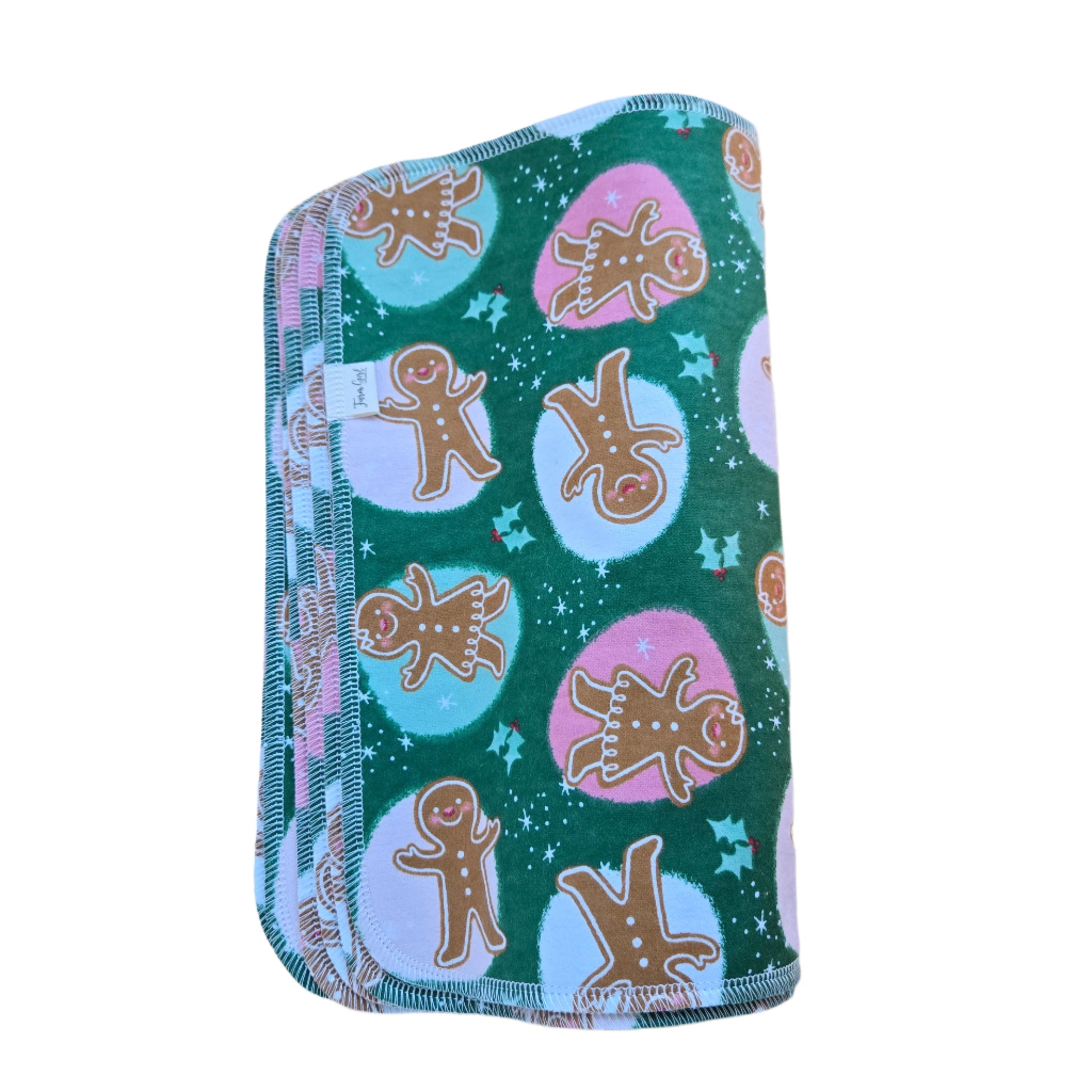 A square-shaped, multicolored paper towel with a gingerbread man and stars pattern, placed on a wooden surface.