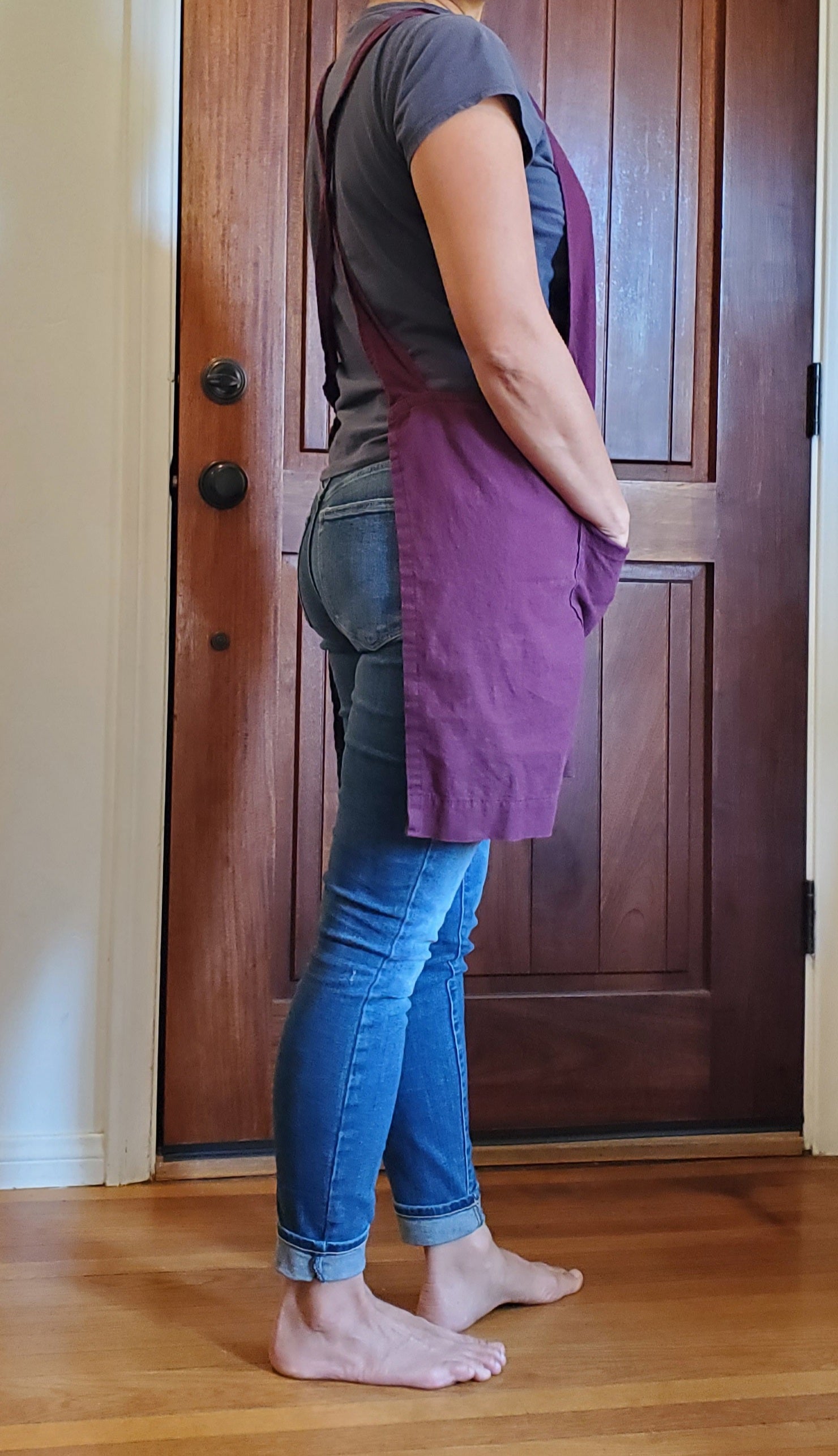 Photo of a barefoot woman wearing a plum colored linen apron by farm girl cloth co.
