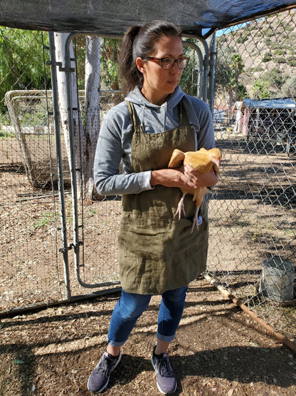 Photo of a woman holding a buff orpington chicken in an olive green linen apron by Farm Girl Cloth Co. 